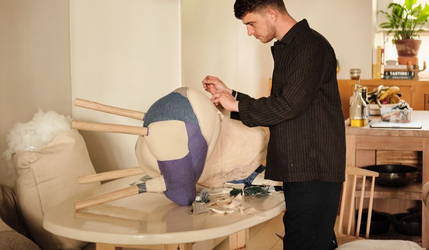 Young Gen Z male mending a footstool on his kitchen table