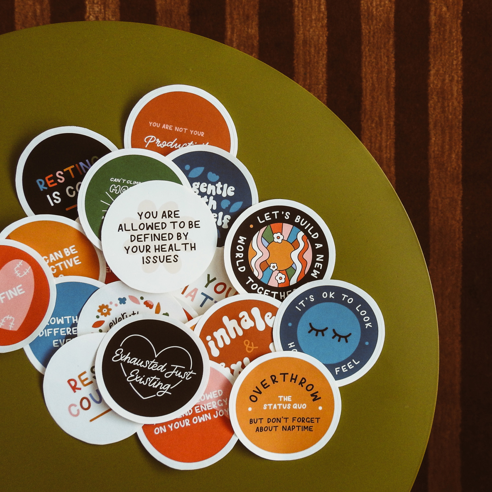 A collection of colourful stickers on a table top with positive slogans about wellbeing.