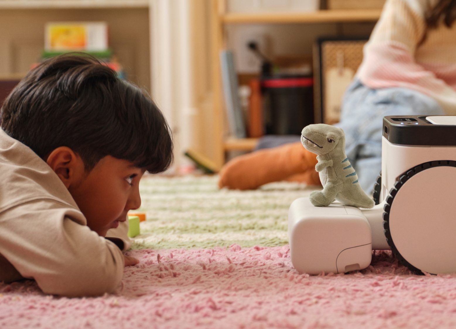 Young boy lying on floor with at-home robot