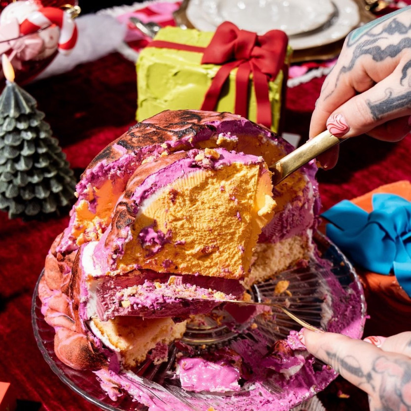 Pink celebration cake on table next to a christmas present