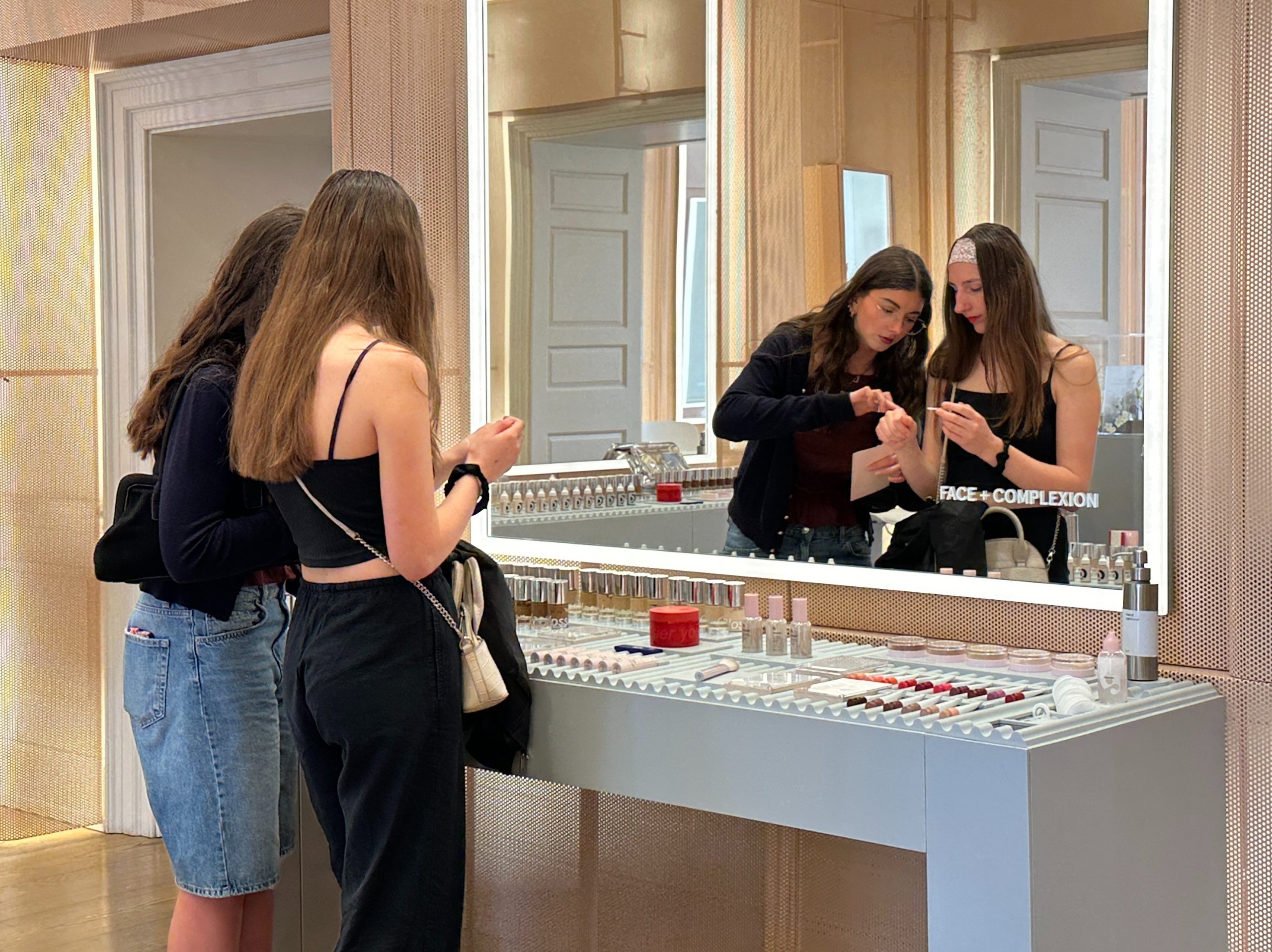 Two teenage girls at beauty counter trying products